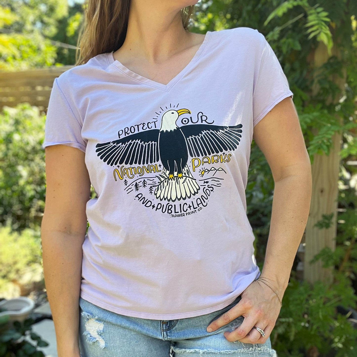 Person wearing a white t-shirt with an eagle graphic and text outdoors. Protect Our National Parks. hand-pulled screenprinted illustration on thrifted apparel, handmade, upcycled apparel