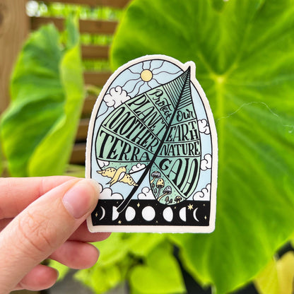A vinyl sticker with a design that includes text and illustrations related to environmental themes, held against an outdoor background with green foliage.