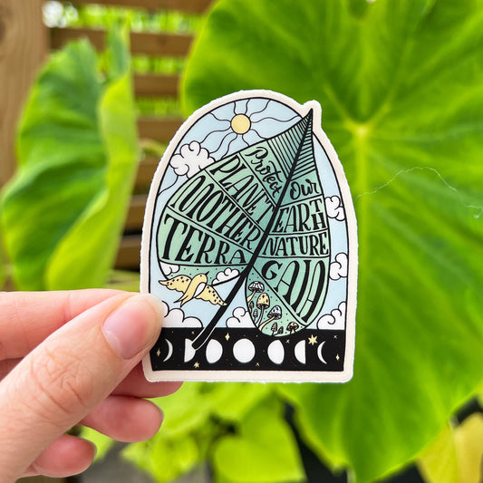 A vinyl sticker with a design that includes text and illustrations related to environmental themes, held against an outdoor background with green foliage.